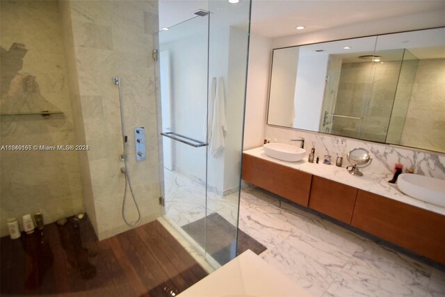 bathroom featuring a shower with door, vanity, backsplash, and wood-type flooring