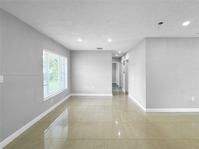 tiled empty room featuring a textured ceiling