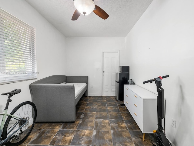 tiled bedroom with ceiling fan, stainless steel refrigerator, and a textured ceiling