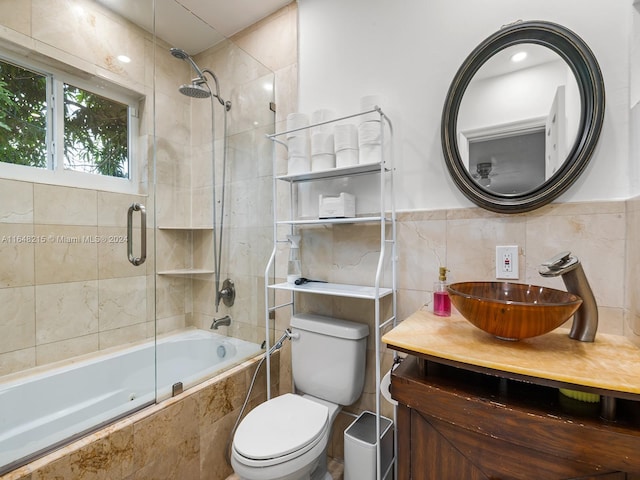 full bathroom with backsplash, toilet, shower / bath combination with glass door, tile walls, and vanity