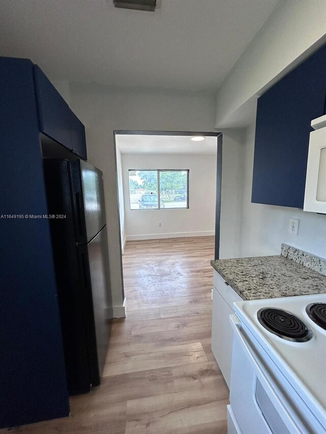 kitchen with light hardwood / wood-style flooring, blue cabinetry, and white appliances