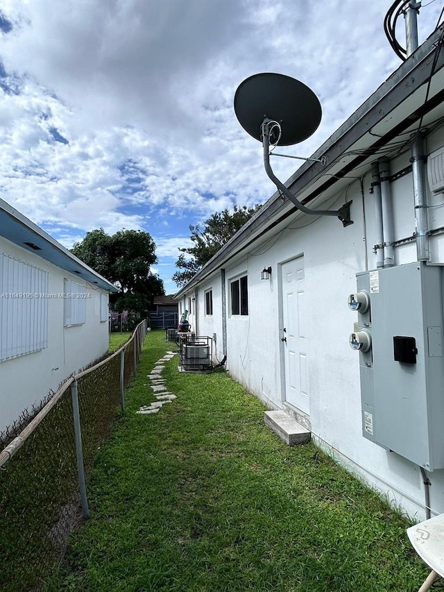 exterior space with central AC and a lawn