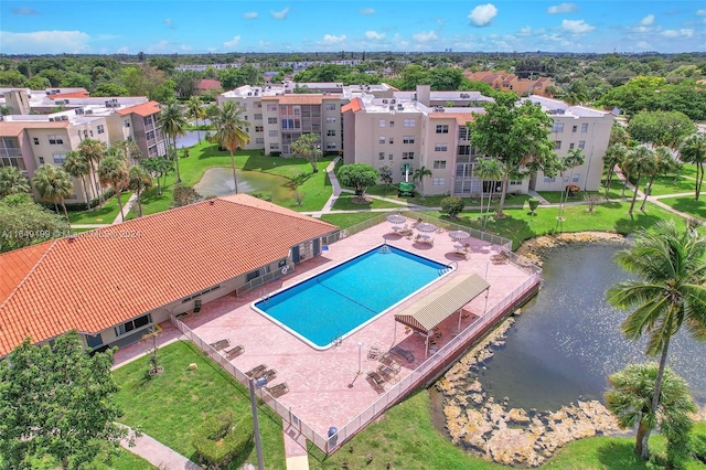 view of swimming pool with a water view, a lawn, and a patio