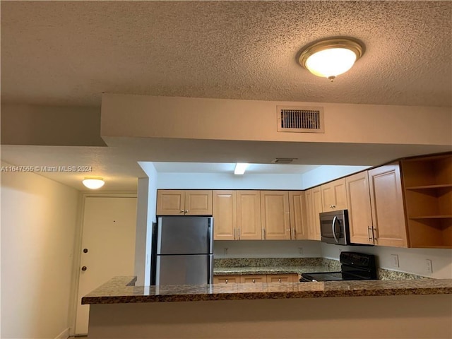 kitchen with dark stone counters, a textured ceiling, kitchen peninsula, appliances with stainless steel finishes, and light brown cabinets