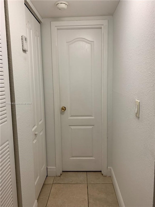 doorway to outside with light tile patterned floors and baseboards