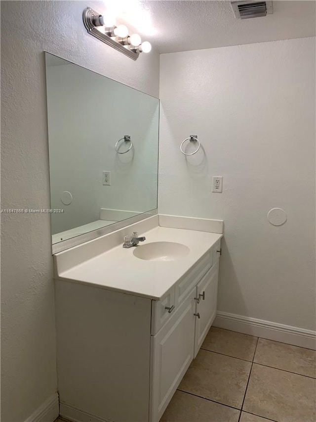 bathroom featuring tile patterned flooring, visible vents, baseboards, vanity, and a textured ceiling