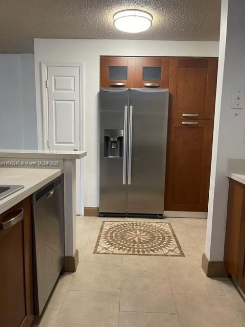 kitchen with appliances with stainless steel finishes, a textured ceiling, and light tile patterned floors