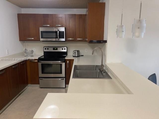 kitchen with stainless steel appliances, sink, and hanging light fixtures