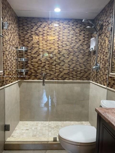 bathroom with walk in shower, vanity, toilet, and tile walls