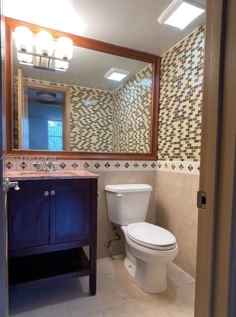 bathroom featuring tile patterned flooring, vanity, tile walls, and toilet