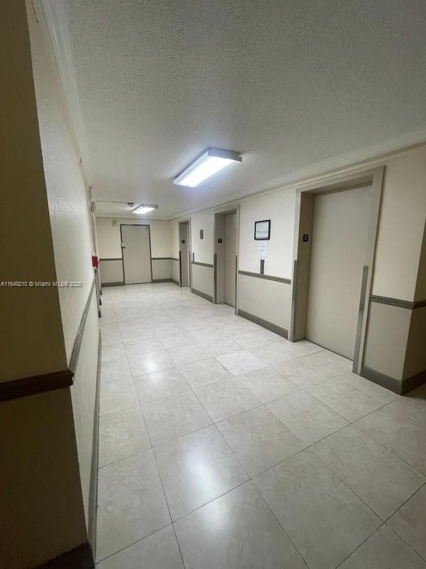 empty room with elevator and a textured ceiling