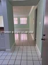 hall featuring baseboards and light tile patterned flooring