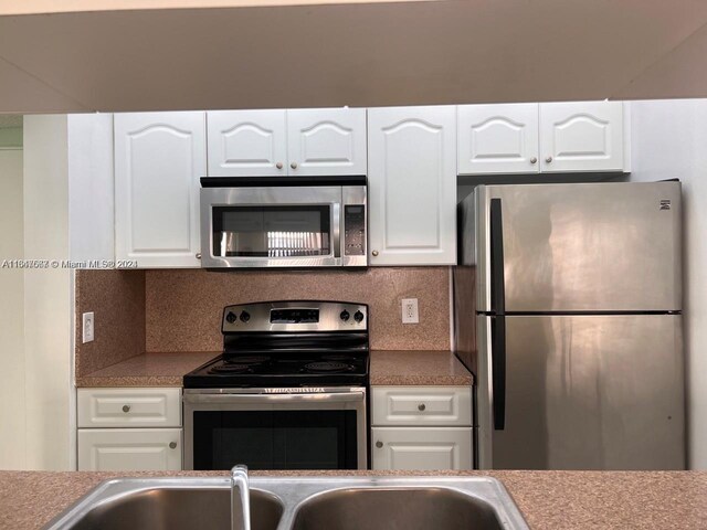 kitchen with appliances with stainless steel finishes, tasteful backsplash, and white cabinetry