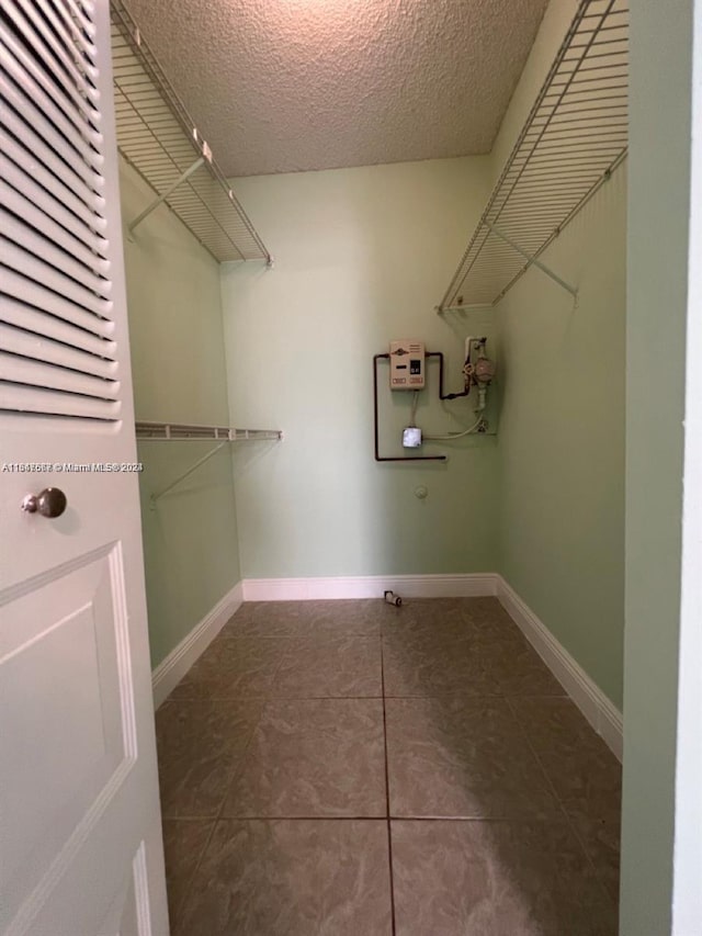 walk in closet with dark tile patterned flooring