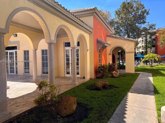 view of side of home featuring a lawn, a patio, and french doors