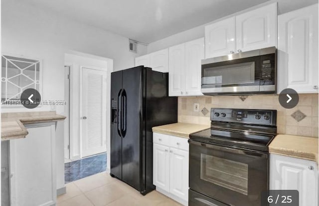 kitchen with black appliances, white cabinets, and light tile patterned flooring