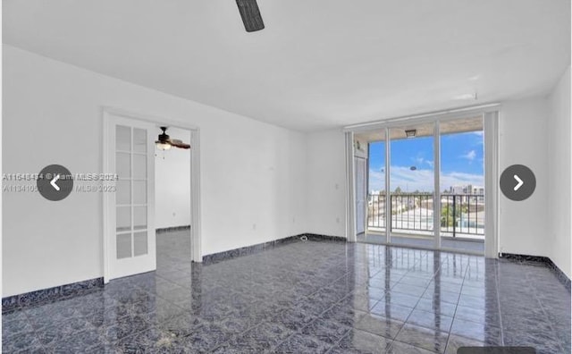 unfurnished room with expansive windows, dark tile patterned floors, and ceiling fan