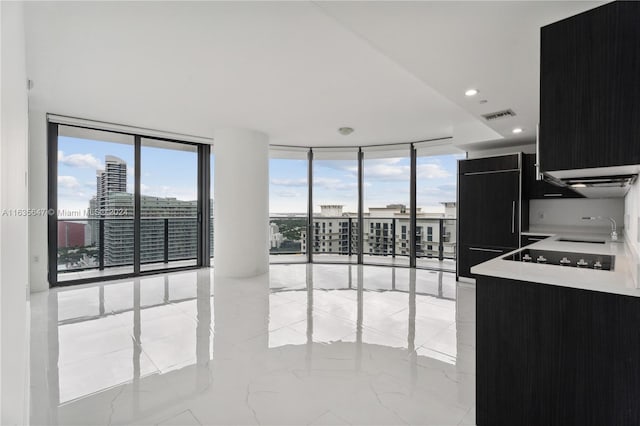 kitchen featuring black electric cooktop, sink, expansive windows, and light tile patterned flooring