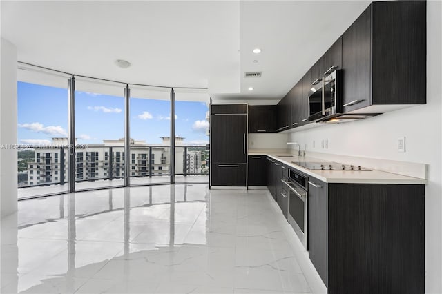 kitchen with appliances with stainless steel finishes, light tile patterned floors, sink, and a wall of windows