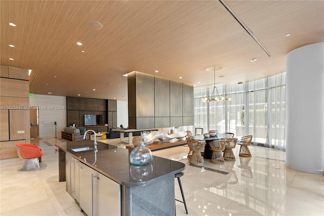 kitchen with dark stone counters, floor to ceiling windows, a center island with sink, and light tile patterned floors