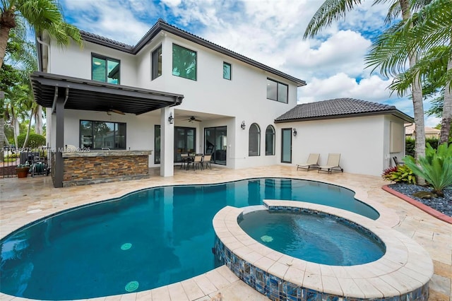 back of property featuring exterior bar, a patio, ceiling fan, and a pool with hot tub