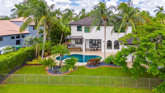 rear view of property featuring a fenced in pool, a yard, and a patio