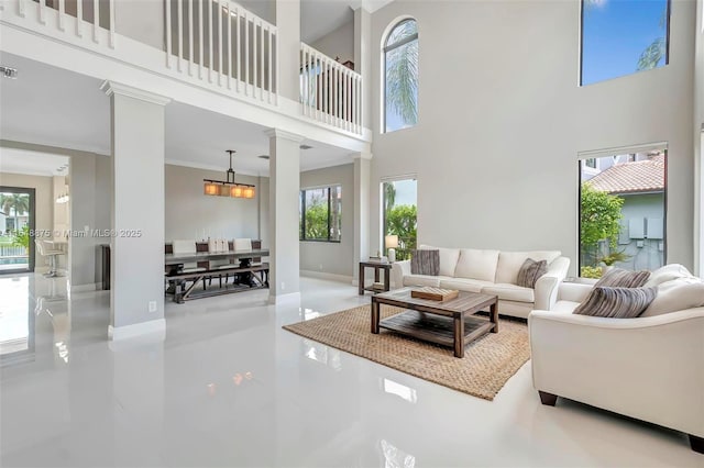 living room with decorative columns, a healthy amount of sunlight, and a high ceiling