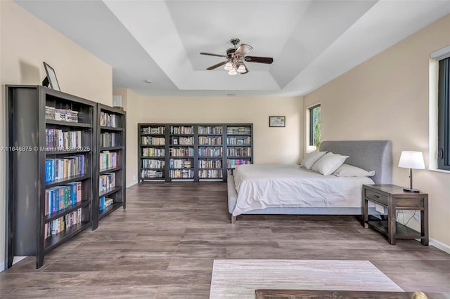 bedroom with a tray ceiling, ceiling fan, and hardwood / wood-style flooring