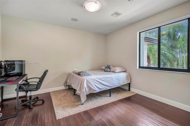 bedroom with multiple windows and dark wood-type flooring