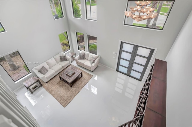 living room featuring french doors, a chandelier, and a high ceiling