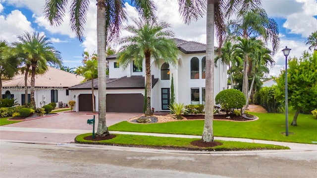 mediterranean / spanish-style house with a garage and a front lawn