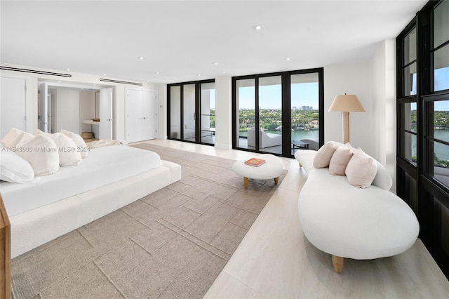 tiled bedroom with a water view, expansive windows, access to exterior, and french doors