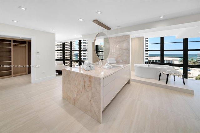 kitchen with a water view, a healthy amount of sunlight, white cabinets, and light tile patterned flooring