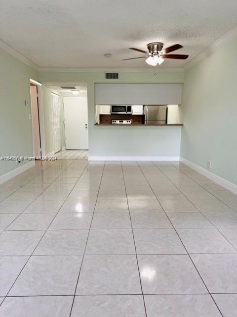 unfurnished living room featuring a textured ceiling, crown molding, ceiling fan, and light tile patterned floors