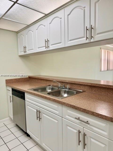 kitchen featuring dishwasher, sink, white cabinetry, and light tile patterned flooring