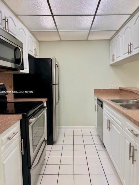 kitchen featuring light tile patterned floors, a paneled ceiling, stainless steel appliances, and sink