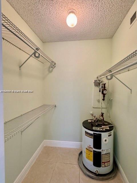 spacious closet with water heater and light tile patterned floors