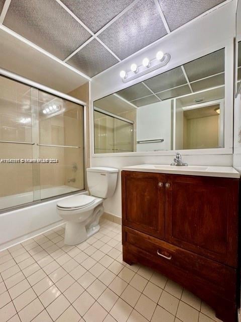 full bathroom featuring combined bath / shower with glass door, vanity, toilet, and tile patterned floors