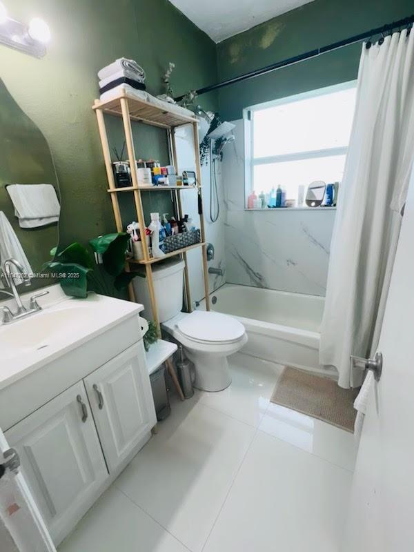 bathroom with shower / tub combo with curtain, vanity, toilet, and tile patterned floors