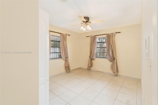 spare room featuring ceiling fan, light tile patterned floors, and a wealth of natural light