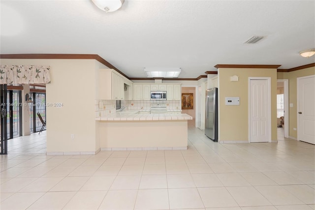 kitchen with stainless steel appliances, tasteful backsplash, kitchen peninsula, tile countertops, and ornamental molding