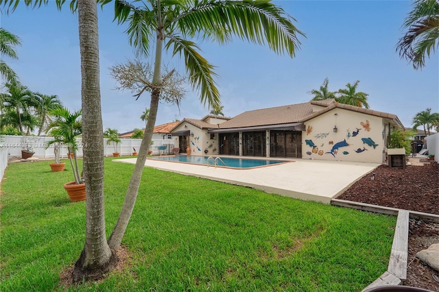 rear view of property featuring a fenced in pool, a yard, and a patio