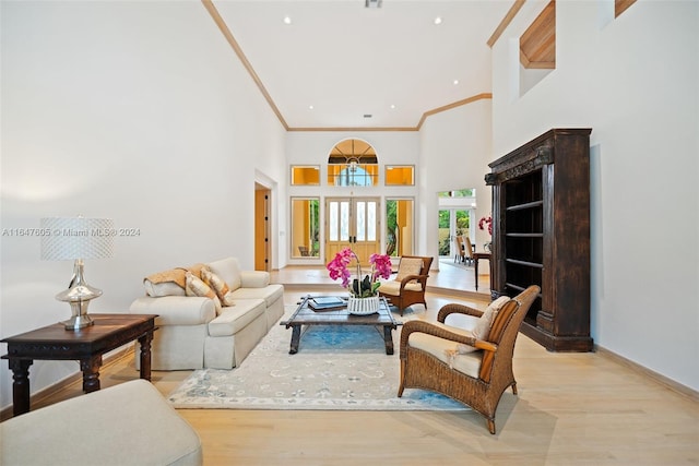 living room featuring light wood-type flooring, crown molding, and a towering ceiling