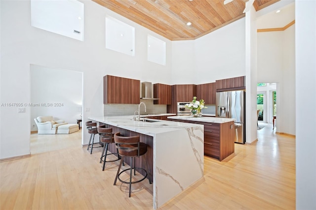 kitchen with a towering ceiling, appliances with stainless steel finishes, kitchen peninsula, and light hardwood / wood-style floors