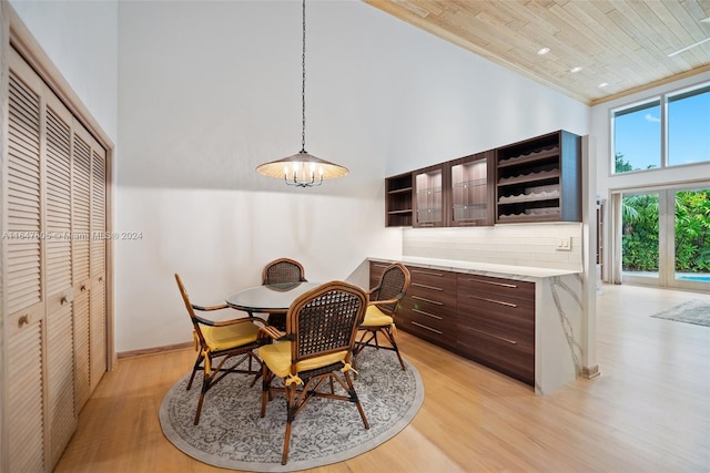 dining area featuring light hardwood / wood-style flooring, crown molding, and a towering ceiling