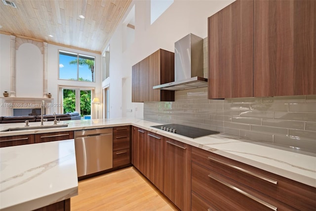 kitchen featuring wall chimney exhaust hood, stainless steel dishwasher, sink, black electric stovetop, and light wood-type flooring