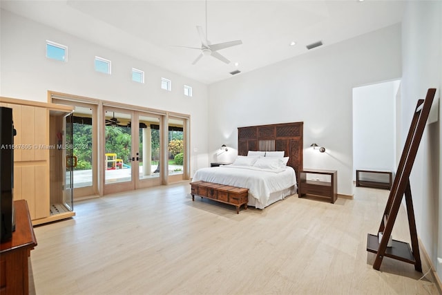 bedroom featuring french doors, light hardwood / wood-style floors, access to outside, ceiling fan, and a towering ceiling