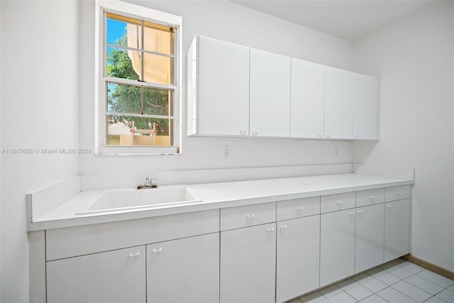 kitchen with white cabinets, light tile patterned floors, and sink