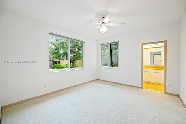 unfurnished bedroom featuring light colored carpet, connected bathroom, and ceiling fan