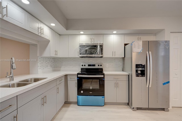 kitchen with light wood-type flooring, appliances with stainless steel finishes, backsplash, and sink